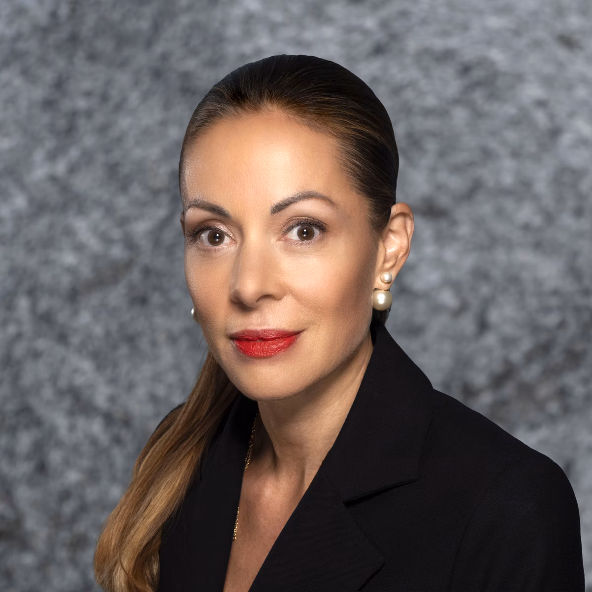 Portrait of a woman with tied-back hair against a grey background