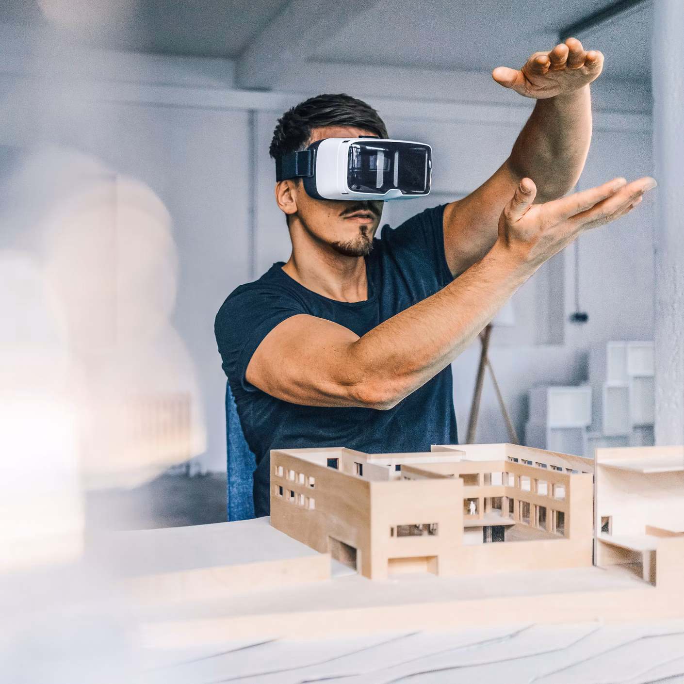 Mann mit VR-Brille betrachtet ein Architekturmodell auf einem Tisch.