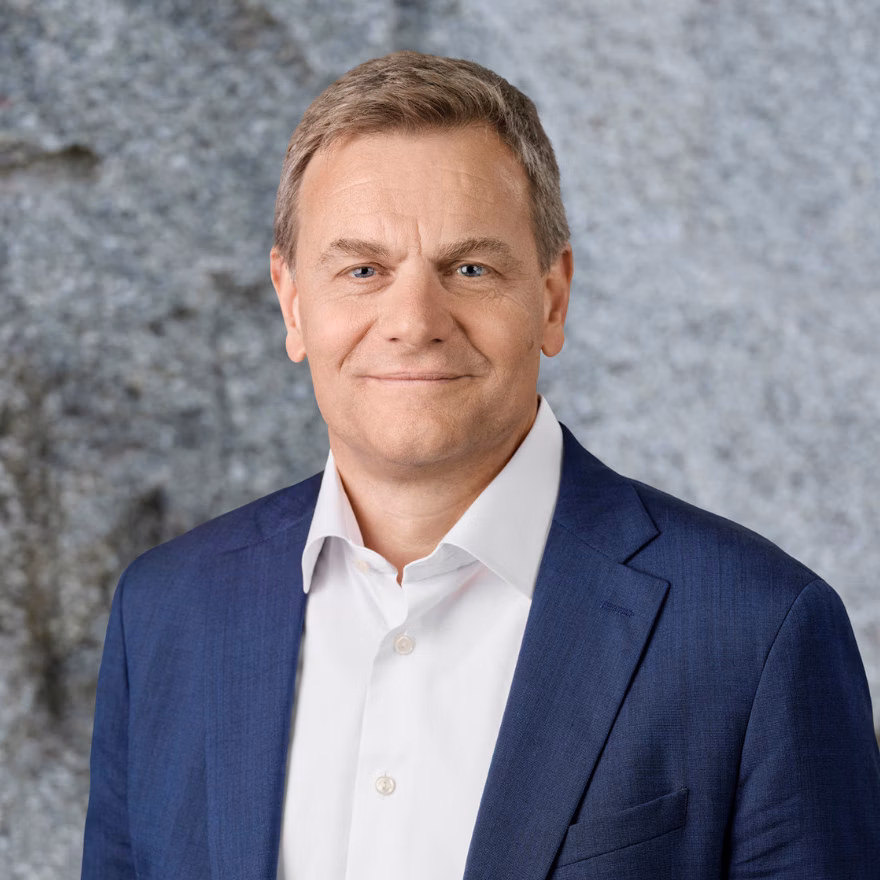 Portrait of a man in a blue suit in front of a grey stone wall