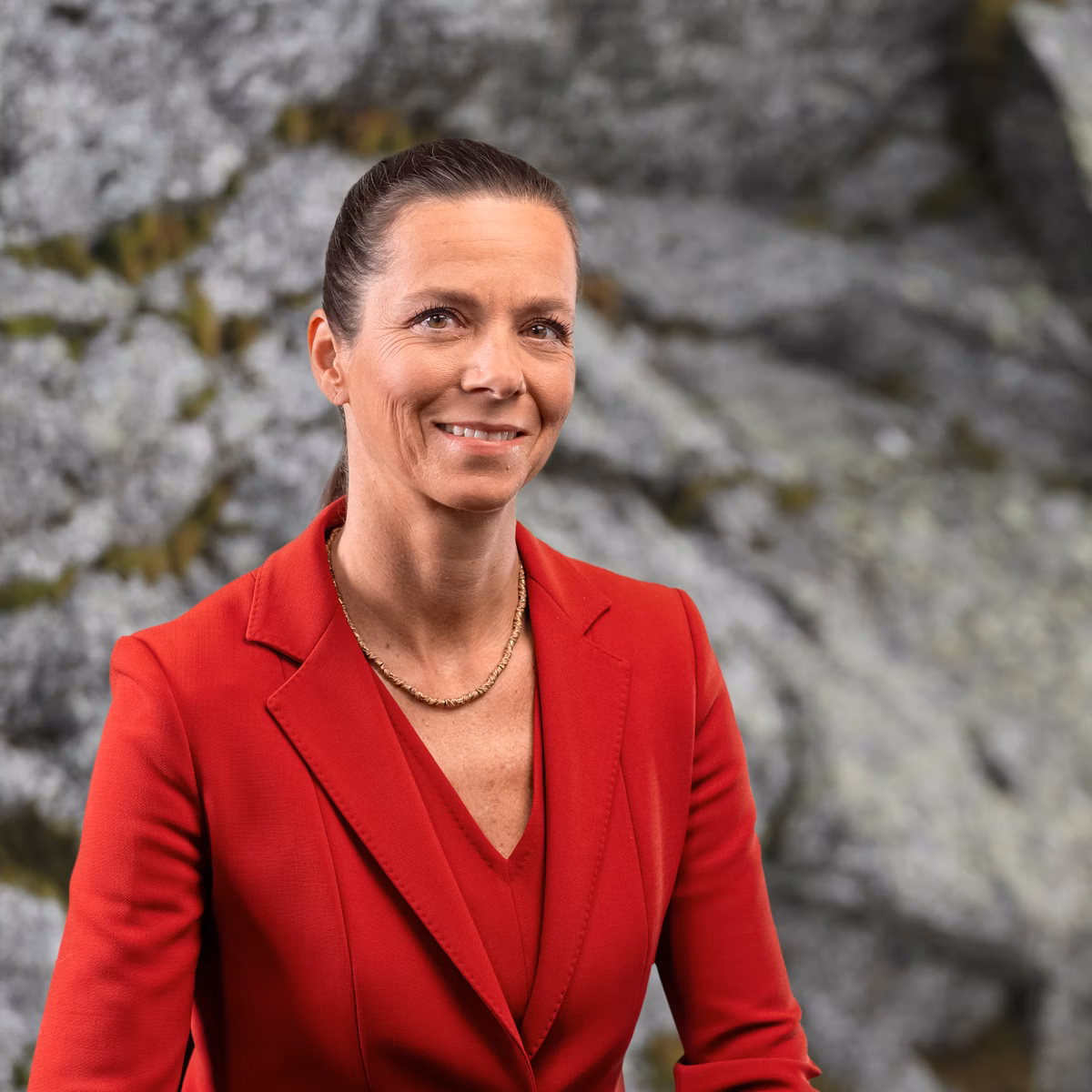 Woman in a red blazer against a rocky background