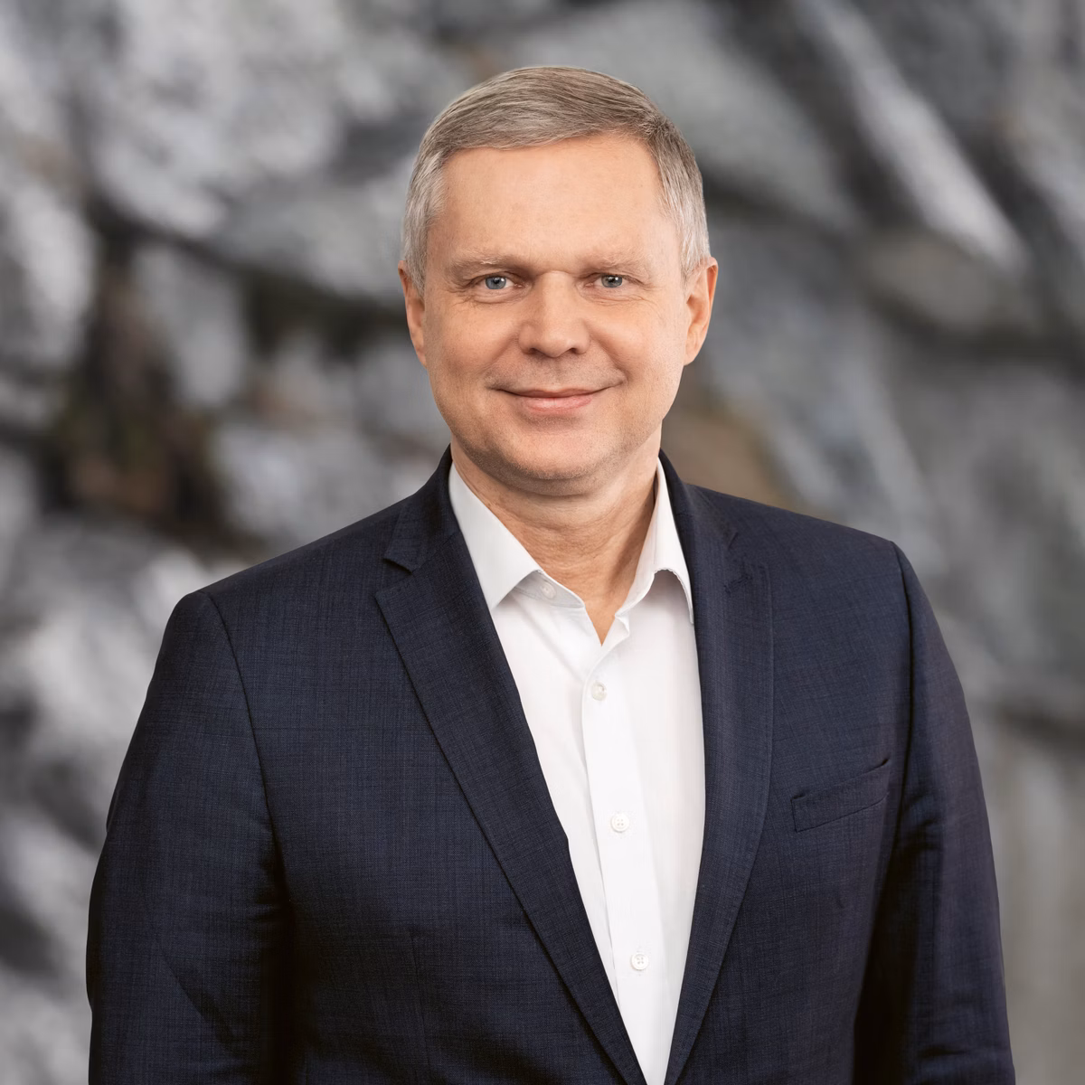 Man in a dark jacket in front of a rock face