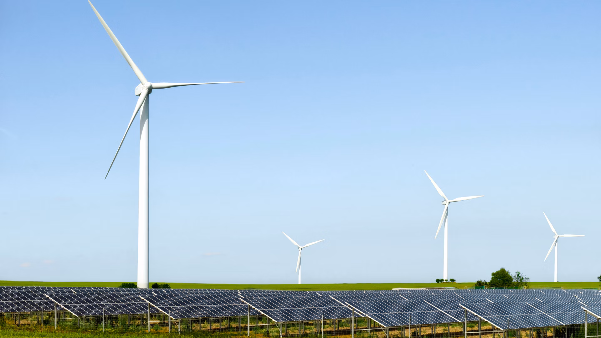 Windräder und Solarpanels auf einem Feld unter klarem Himmel